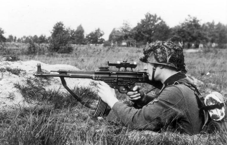 Um soldado demonstrando a variante de transição MP 43/1, utilizada para determinar a adequação do fuzil para efeitos de arrebatamento, em outubro de 1943. O fuzil está equipado com uma visão telescópica ZF 4